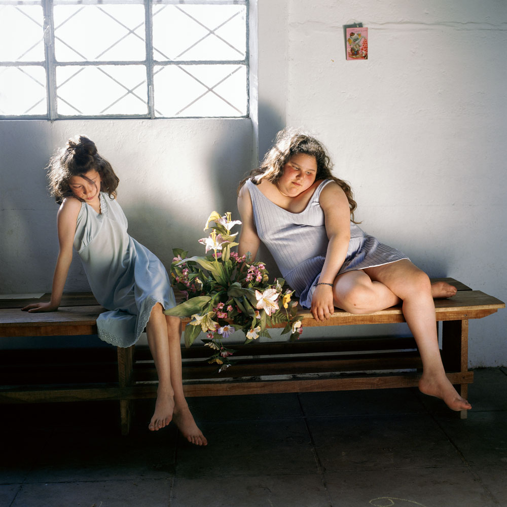 Alessandra Sanguinetti, Square Print Sale,“The Models,” of Argentinian protagonists Guille and Belinda as they pose in front of a white wall with a bouquet of fresh flowers, illuminated by the rays of light coming from the window behind them