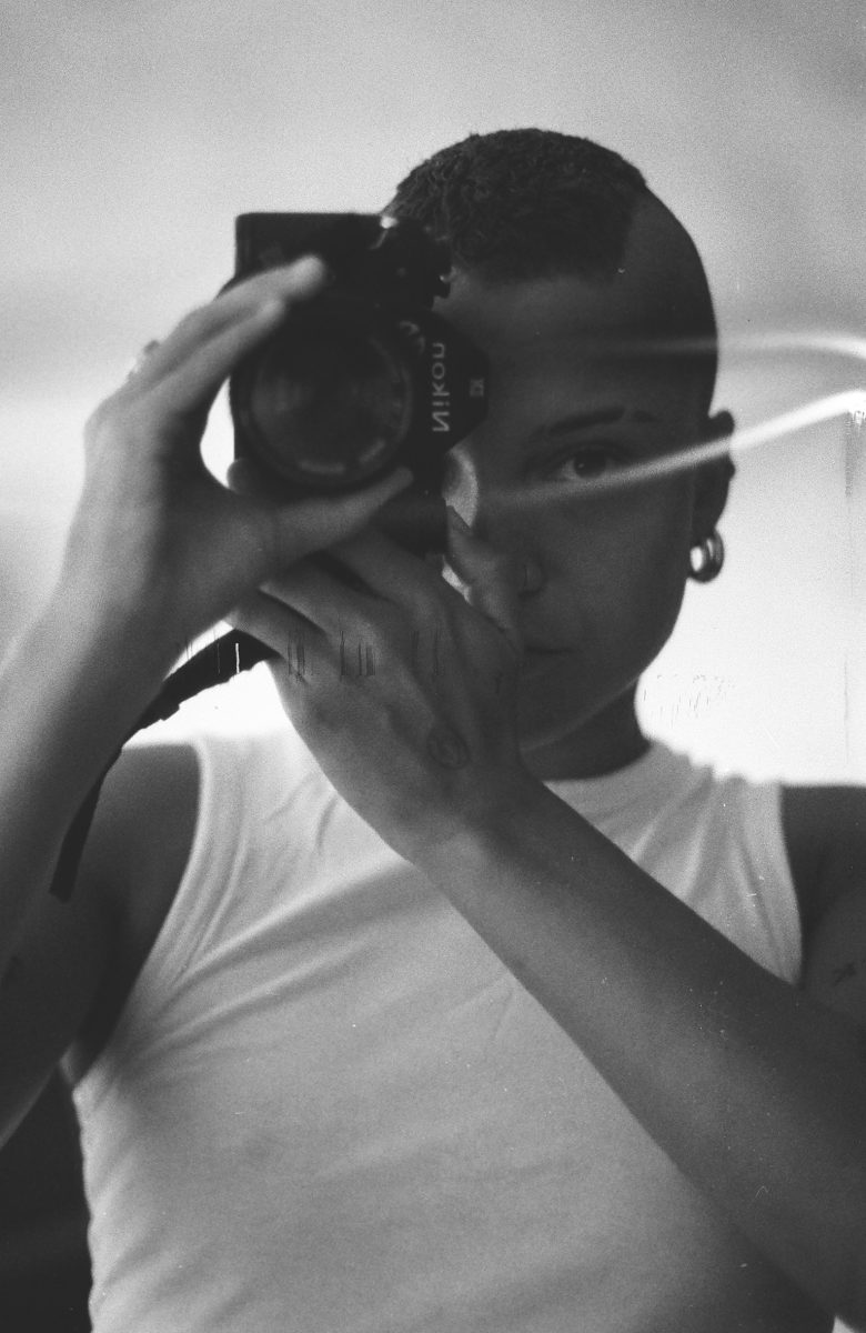 Alternative Text: Black and white self-portrait photograph ofRene Mati? holding a camera to their face. 