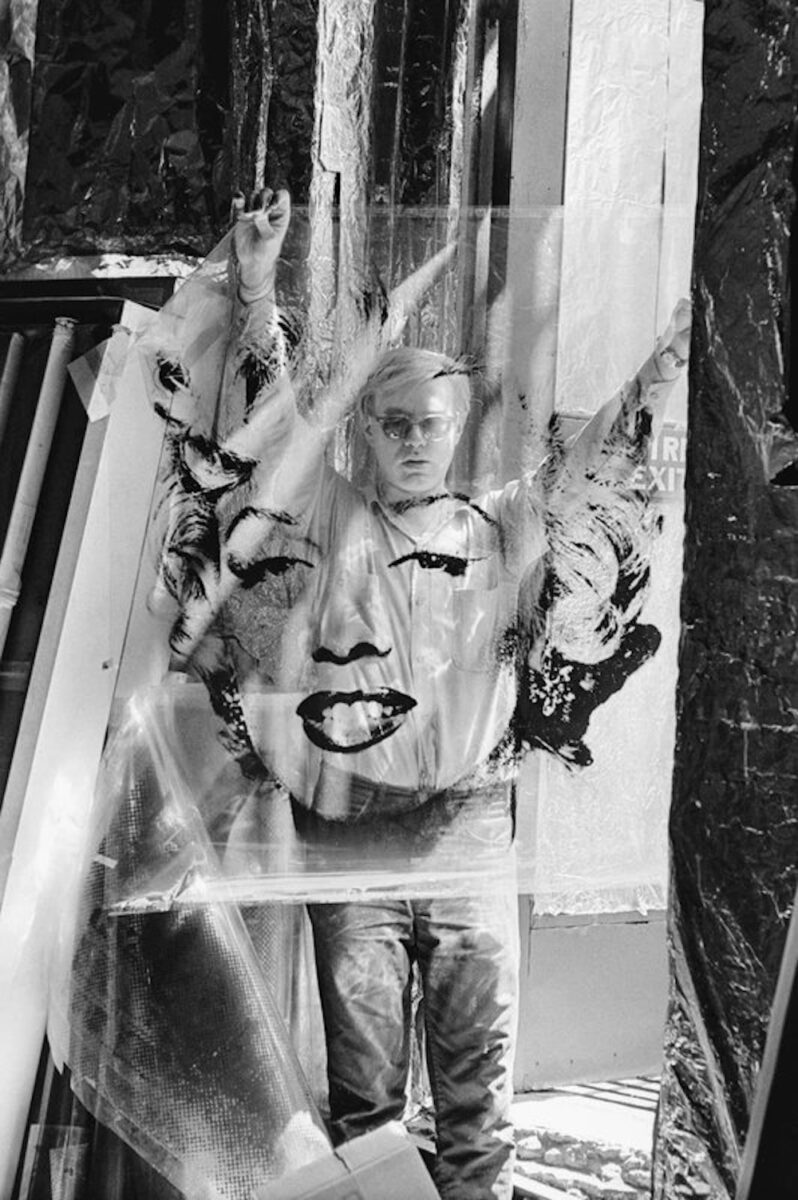 William John Kennedy ANDY WARHOL HOLDING MARILYN MONROE ACETATE, 1964, THE FACTORY, NY GELATIN SILVER PRINT 22 1/4 × 15 1/4 in | 56.5 × 38.7 cm Frame included hand signed by WJK