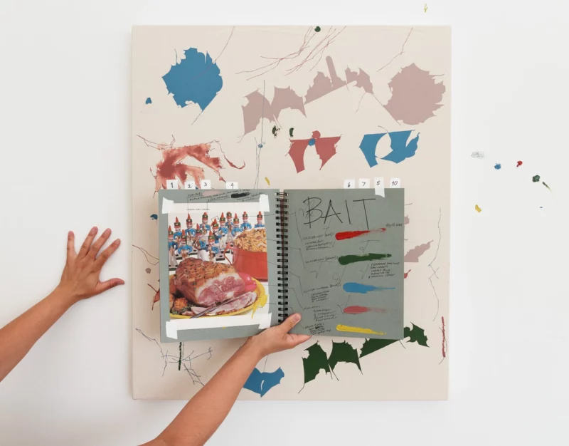 Maysha Mohamedi with sketchbook and corresponding painting (Bait, 2023) at her Los Angeles studio. Photo by Megan Cerminaro © Maysha Mohamedi